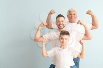 Man with his father and son showing muscles on color background�