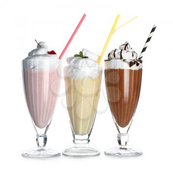 Glasses of tasty milkshakes on white background�