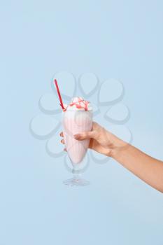 Female hand with glass of tasty milkshake on color background�