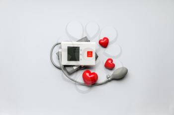 Electronic sphygmomanometer and red hearts on light background�