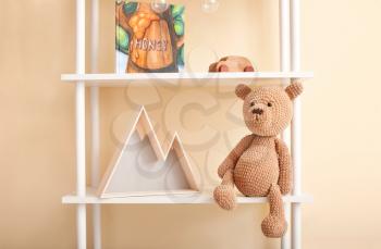 Shelf with baby toys, book and decor near color wall�