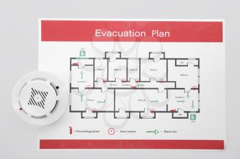 Evacuation plan and smoke detector on white background�