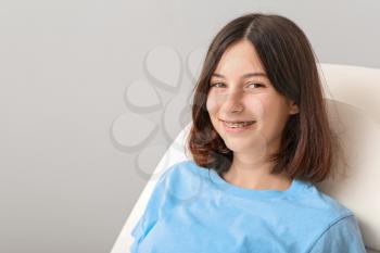 Teenage girl with dental braces sitting in dentist's armchair�