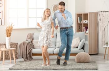 Happy dancing young couple at home�
