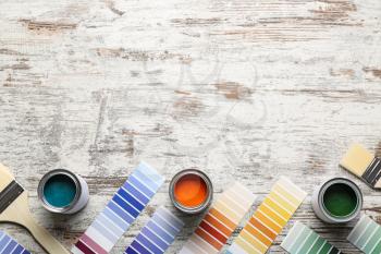Color swatches with paints and brushes on wooden table�