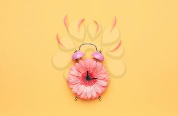 Creative alarm clock made with flower on color background�