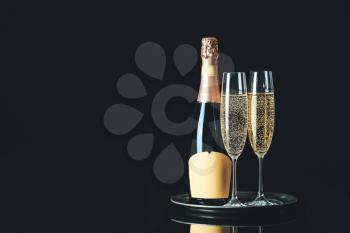 Glasses and bottle of tasty champagne on dark background�