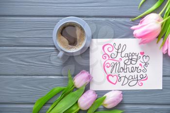 Beautiful greeting card with flowers for Mother's day and cup of coffee on wooden background�