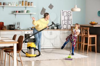 Young woman with her little daughter having fun while cleaning kitchen�