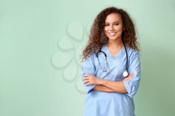 Young African-American nurse on color background�