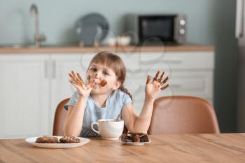 Cute little girl eating chocolate in kitchen�