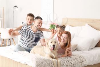 Happy family with dog in bedroom at home�