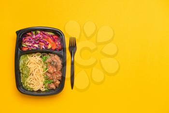 Container with healthy food on color background�