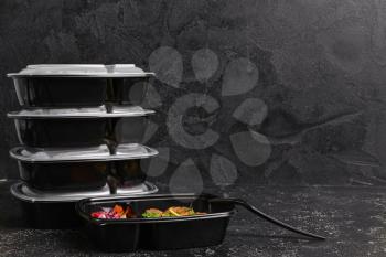 Containers with healthy food on dark background�