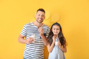 Father and daughter drinking milk with cookies on color background�