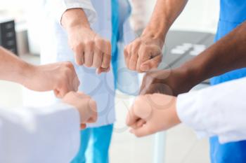 Group of doctors putting hands together in clinic. Unity concept�