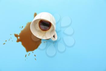 Overturned cup of coffee on color background�
