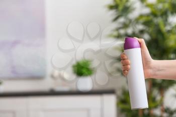Woman spraying air freshener at home�