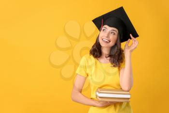 Female graduating student with books on color background�