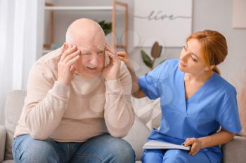 Elderly man suffering from mental disability and caregiver in nursing home�
