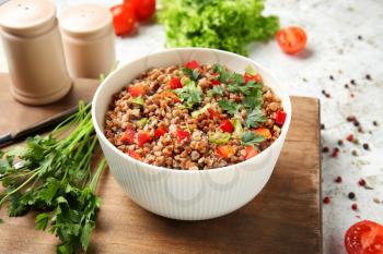 Bowl of tasty buckwheat porridge and vegetables on table�