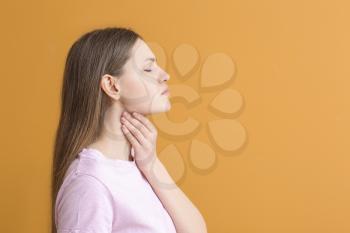 Young woman checking thyroid gland on color background�