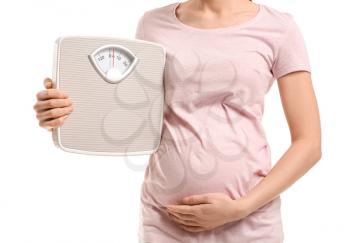 Young pregnant woman with measuring scales on white background�