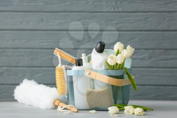 Set of cleaning supplies and spring flowers on grey wooden background�
