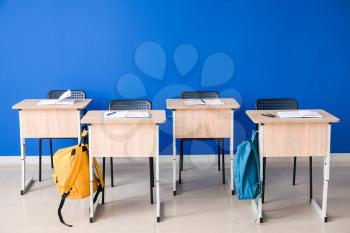 Modern school desks near color wall�