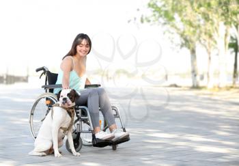 Young woman in wheelchair and her service dog outdoors�