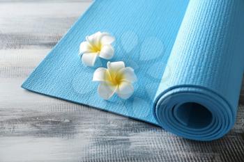 Color yoga mat and flowers on wooden background�