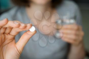 Woman holding pill, closeup�