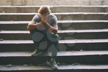 Stressed young man sitting on stairs outdoors�