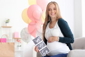 Beautiful pregnant woman with sonogram image at baby shower party�
