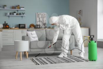 Worker in biohazard suit disinfecting house�
