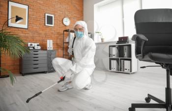 Worker in biohazard suit disinfecting office�