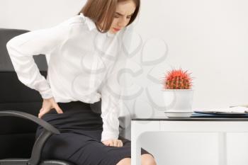 Young businesswoman with hemorrhoids in office�