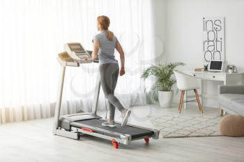 Sporty woman training on treadmill at home�