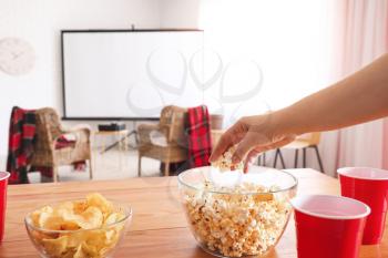 Woman eating popcorn while watching movie at home�