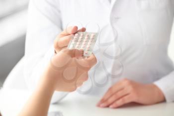 Female gynecologist and patient with birth control pills in clinic, closeup�
