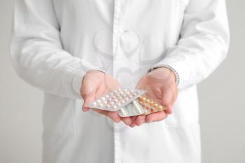 Female gynecologist with birth control pills on grey background, closeup�