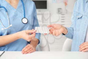 Female gynecologist and patient with birth control pills in clinic�