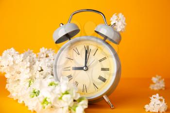 Alarm clock and flowers on color background. Spring time�