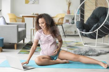 Young pregnant woman practicing yoga at home�