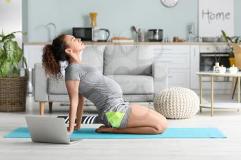 Young pregnant woman practicing yoga at home�