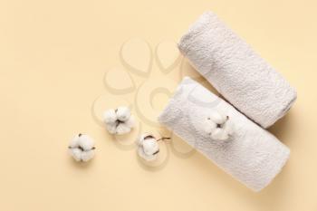 Cotton flowers and soft towels on color background�