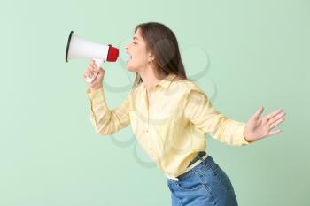 Beautiful young woman with megaphone on color background�