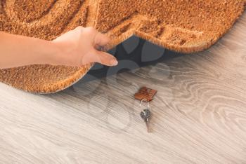Woman putting spare key under door mat�