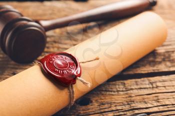 Scroll with notary public wax seal and gavel on table, closeup�