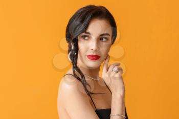 Beautiful young woman wearing stylish jewelry on color background�